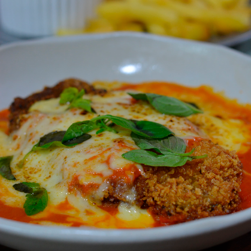 Parmegiana com queijo derretido, manjericão e batatas fritas